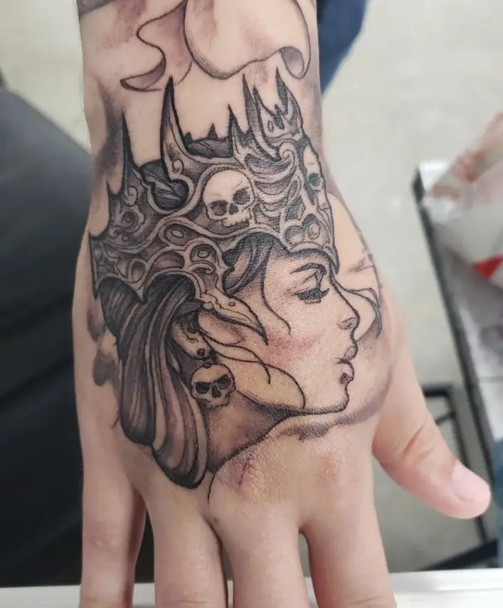 Hand tattoo woman's head with crown. Black and gray