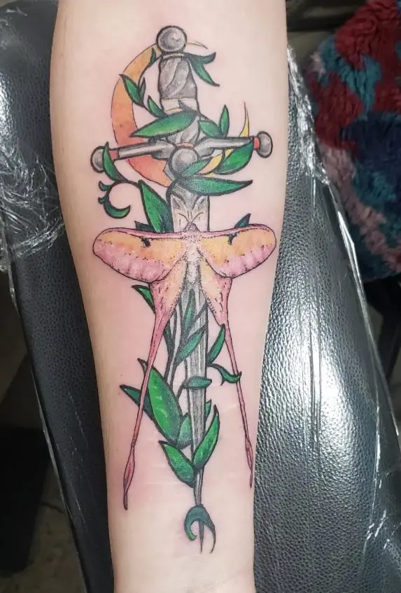 Colorful moth and dagger tattoo with moon on forearm