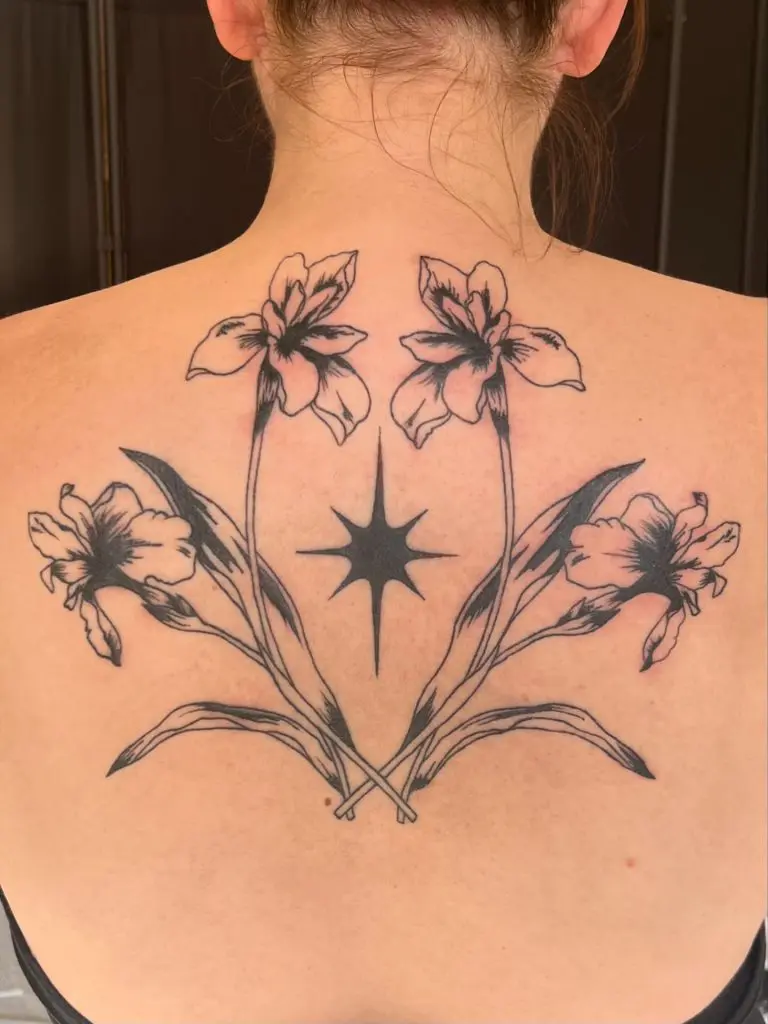 Ornamental blackwork lilies and stars across the upper back by Fae