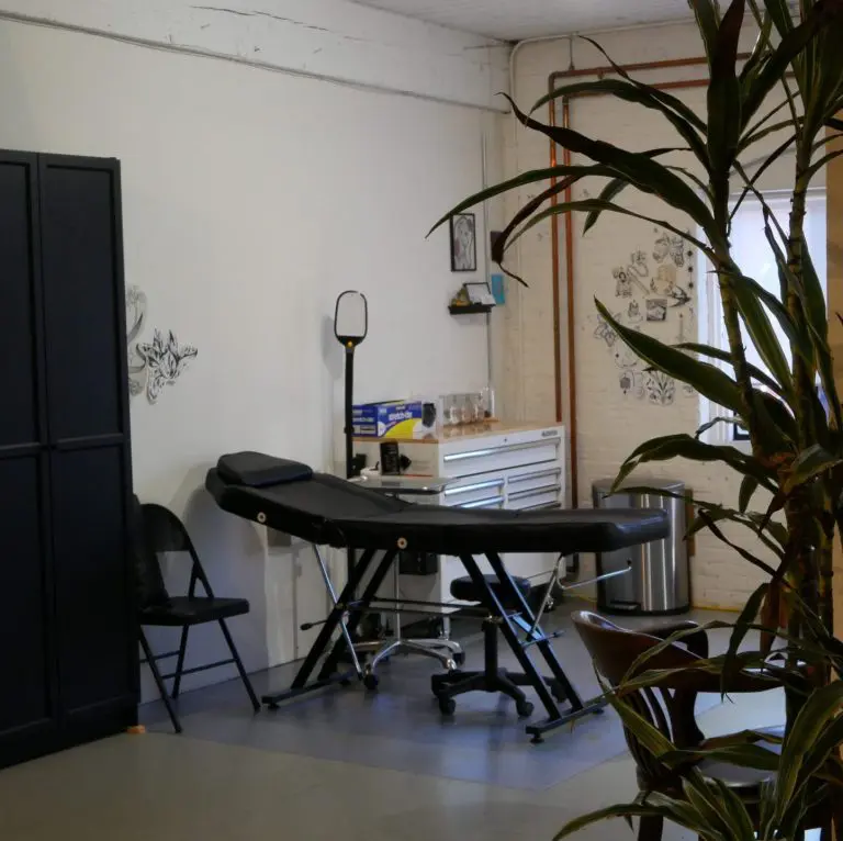 A tattoo station with a black chair and rolling cart