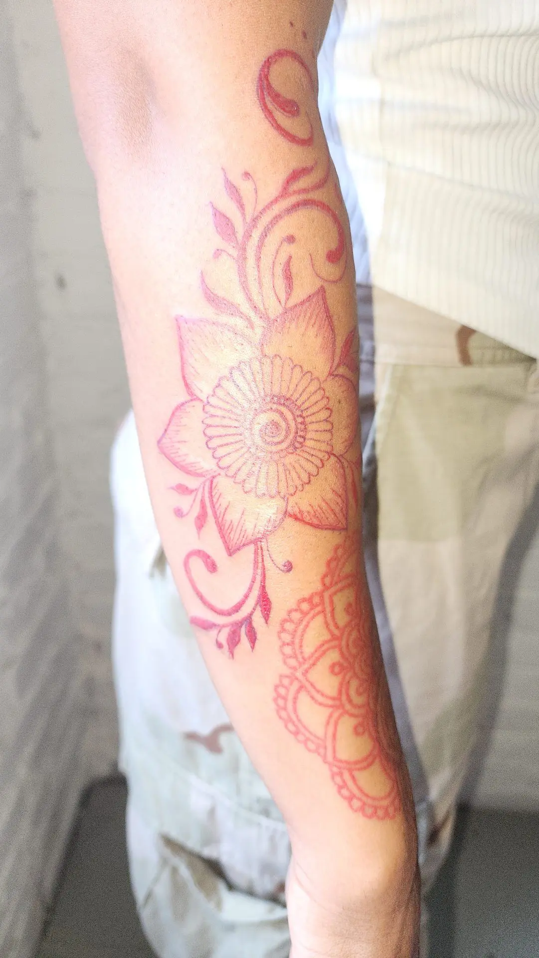 Red ink floral and mandala piece running down a forearm